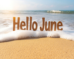 Summer greeting, Hello June on a sandy beach.  Ocean waves gently touch the words