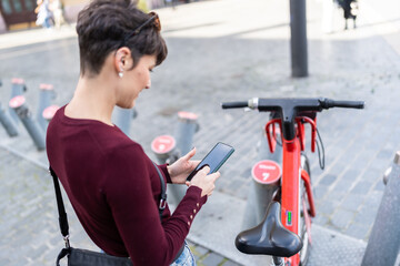 Woman using smartphone unlocking public sharing bicycle