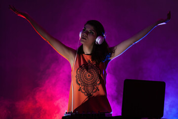 Girl DJ playing music on a mixer. Purple red and blue smoke in the background
