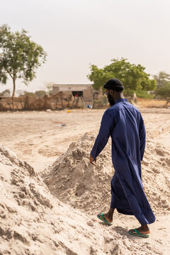 Senegalese man walking on sand piles in Senegal, Africa