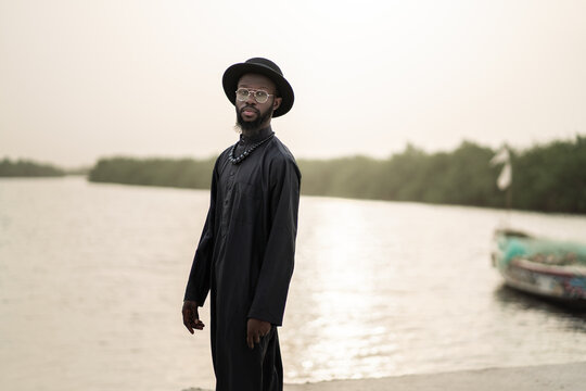 Senegalese man wearing traditional clothes posing near a river