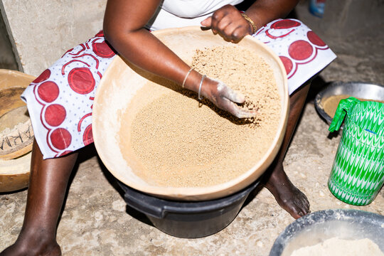 Woman preparing traditional Senegalese couscous in large wooden bowl