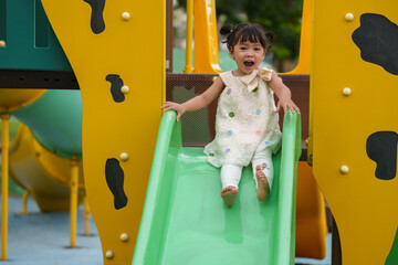happy toddler baby girl sliding and playing at playground