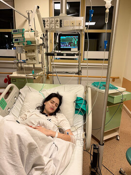 A young woman lies in a hospital bed in an intensive care unit