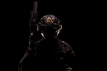 Silhouetted soldier holding a rifle with tactical gear in low light