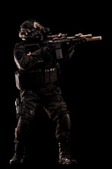 Special forces soldier with weapon in tactical gear on black background