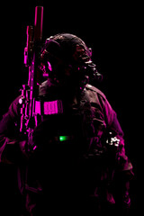 Tactical soldier in dark environment illuminated by vibrant pink and green lighting