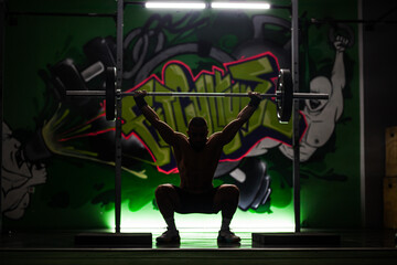 Athlete performing a weightlifting exercise in a gym with vibrant graffiti