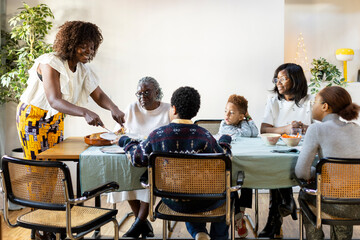 Smiling mother serving food at family Christmas lunch