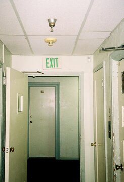 Dimly Lit Hallway with Exit Sign and Open Doors