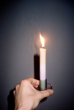 Hand Holding a Burning Candle in the Dark