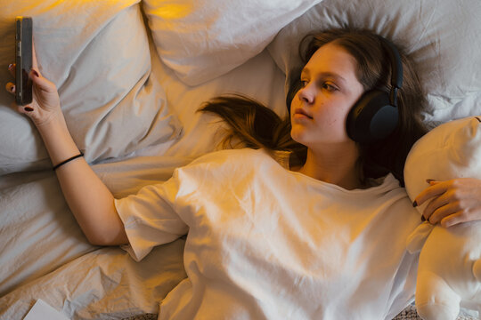 Teenager relaxing at home while listening to music with headphones