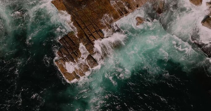 waves crash and wash dramatically over slab of rocks