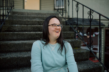 Smiling Individual Sitting on Steps Outdoors on a Casual Day