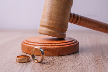 Wooden gavel and wedding rings on wooden background. Family law and divorce concept.