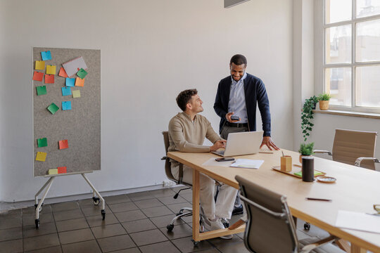 Two formal businessmen collaborating on laptop in modern office
