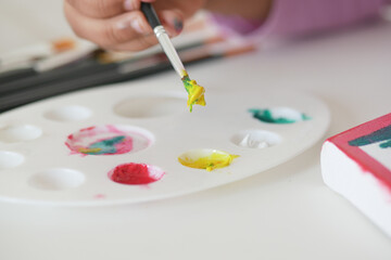 Child engages in creative painting activity at a bright workspace