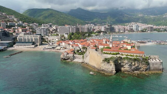 Aerial droen view Budva old town Stari harbour yachts Medieval Dubrovnik blue waters riviera mountains vacation holiday coastal Adriatic Mediterranean 