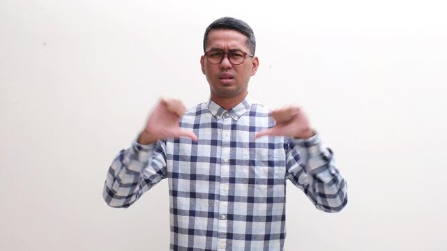 Adult Asian man showing disappointed expression and give thumbs down