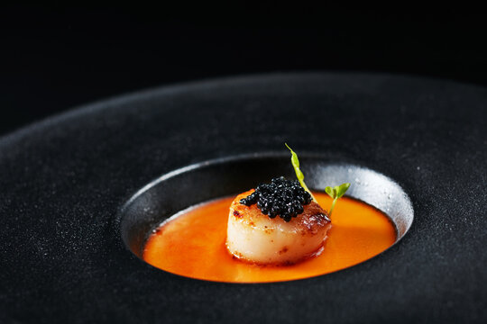 Closeup of steamed egg with fish roe and scallops in black plate