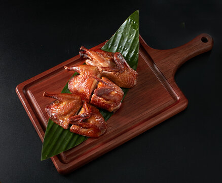 Closeup of roasted pigeon on a wooden plate