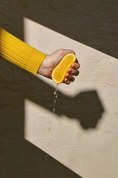 Hand Squeezing Orange with Juice Dripping in Natural Light