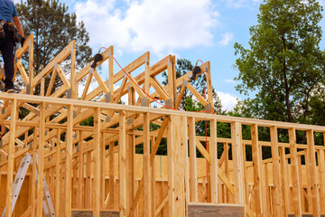 Workers in safety gear are installing wooden trusses on building under construction