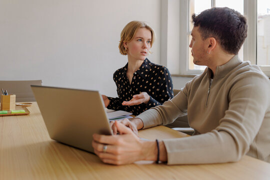 Two business colleagues using laptop in office meeting