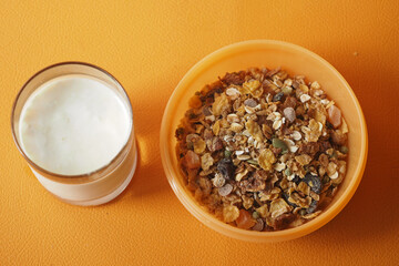 Morning breakfast with cereal and milk on a vibrant orange table
