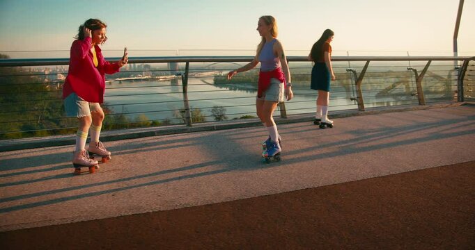 Multicultural Women in Casual Clothes Riding Roller Skates. Fit Beautiful Friends Moving and Spinning Around while Entertaining during Sunrise. Fitness Youth Culture Diversity