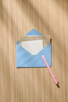 Blue Envelope with Stationery and Pink Pen on Wooden Surface