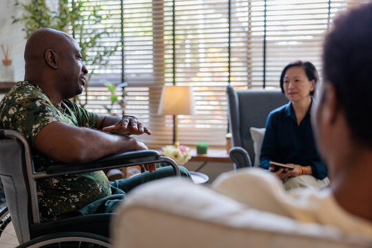 Sad man in wheelchair discussing with psychotherapist during session