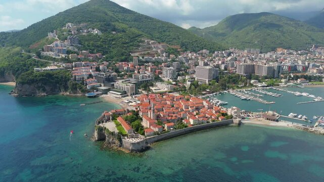 Aerial droen view Budva old town Stari harbour yachts Medieval Dubrovnik blue waters riviera mountains vacation holiday coastal Adriatic Mediterranean 