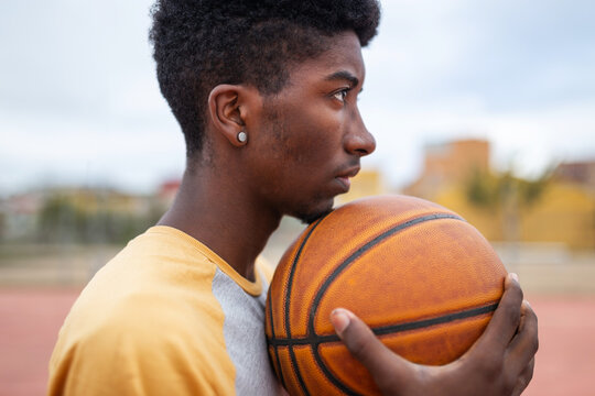 Portrait of a Black Teenager Holding a Basketball on a City Court