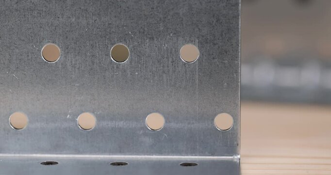corner with a lot of holes for connecting wooden parts with screws, metal products for connecting wooden structures, closeup