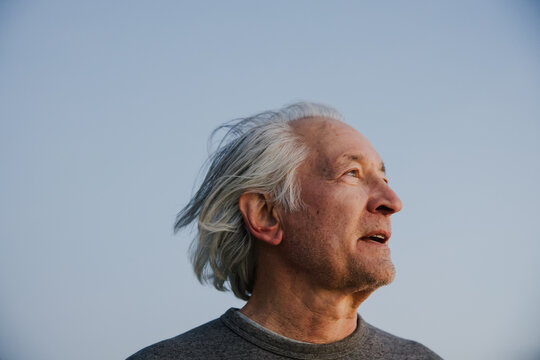 Thoughtful Elderly Man Looking Towards the Horizon During Twilight