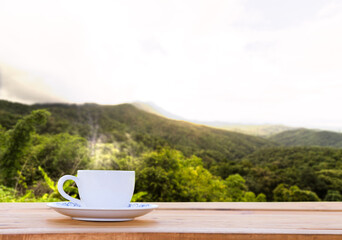 Cup of hot coffee on a wooden table, natural scenery backdrop, mountain views, Warm morning sunlight