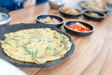Traditional Korean Food, Korean green onion pancake with side dishes, Korean scallion pancake, Pajeon in a black plate and side dish on table