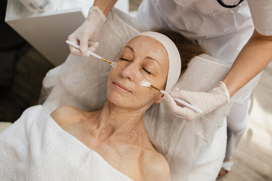 Beautician with brushes massaging client