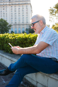 Happy middle-aged man using mobile phone in the city