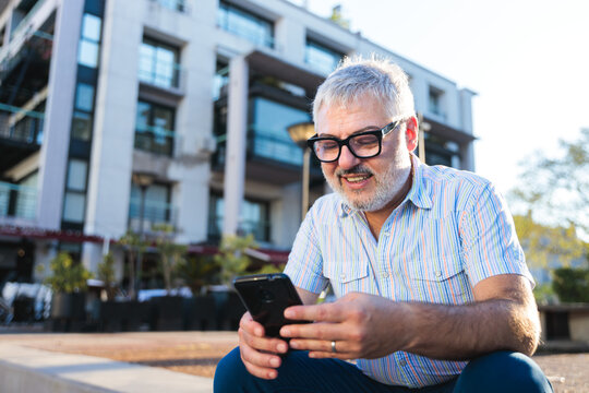 Mature man using smartphone in urban setting