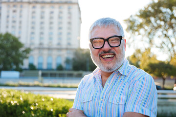 Happy mature man smiling in the city at sunset