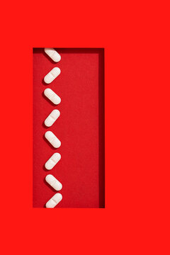 White tablet pills aligned in a row on rectangular red background