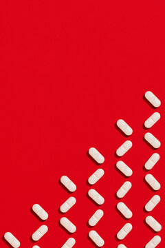 White tablet pills aligned in a triangular pattern on red background