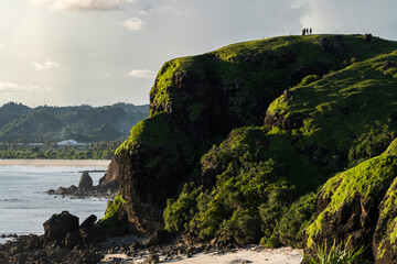 Travel friends standing on green cliff at sunset