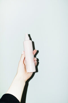Hand holding a beauty product spray bottle with hard direct flash