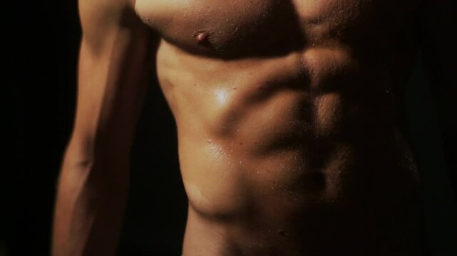Muscular nude man flexing his body. Sexy male torso closeup. Shirtless man showing abs and muscles. Athletic male body in dramatic lighting. Sexy muscular man posing nude. Guy flexing muscles.