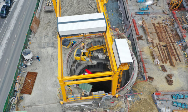 a crane lowers an excavator underground
