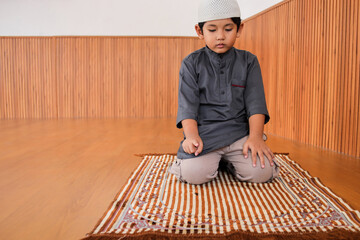 Muslim Boy Praying In Tashahhud Posture In Sitting Position For Last Salah Movement Before Finished