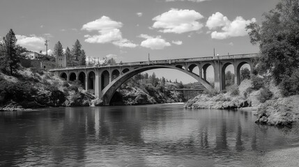 Obraz premium Black and white view of a large arch bridge over a river.